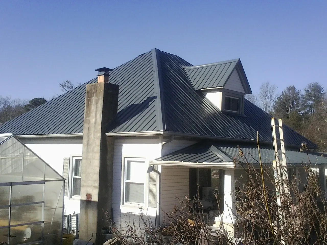 Dark blue standing seam metal roof on a white farmhouse with dormer — Slate & Tile Roof Repair by Roofing Brothers in Bethel Park