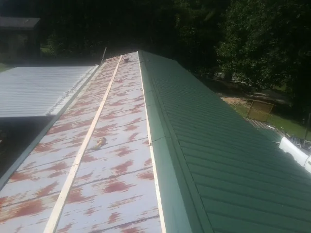 Old rusted panels beside newly installed green metal roofing — Wind Damage Roof Repair by Roofing Brothers in Bethel Park