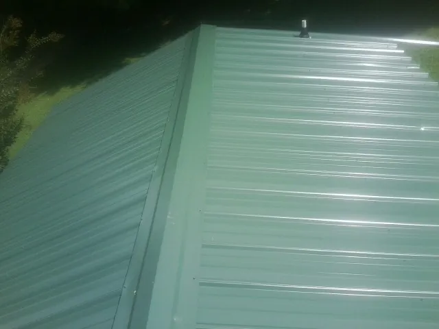 New green metal panels meeting at the ridge of a roof — Flat Roof Repair work by our crew in Bethel Park