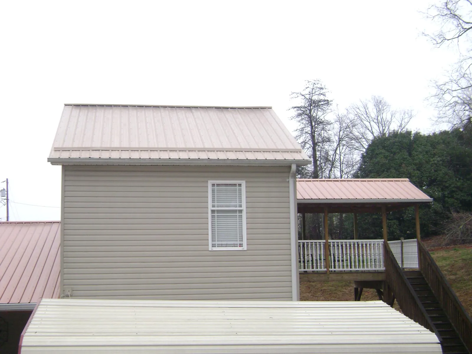 Tan metal roofs on a two story addition and attached porch, from a Roof Replacement job in Bethel Park