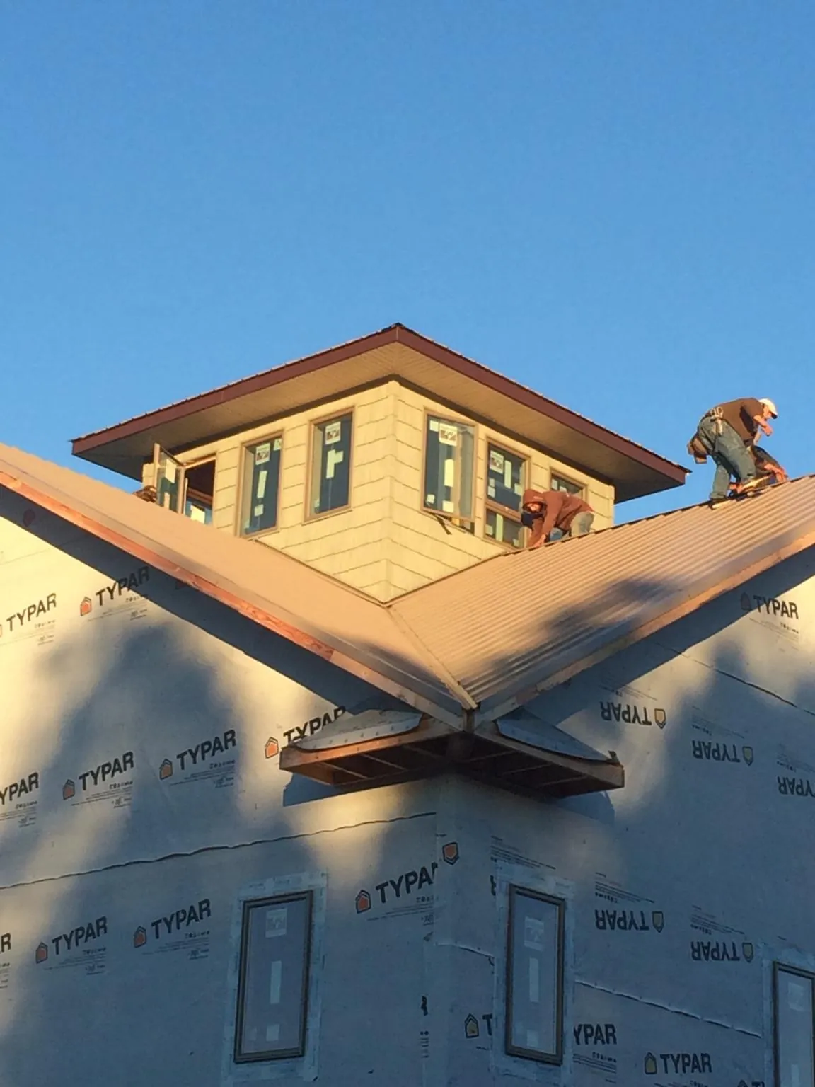 Roofers working around a rooftop cupola on a new metal roof at sunset — Roof Waterproofing in Bethel Park by Roofing Brothers